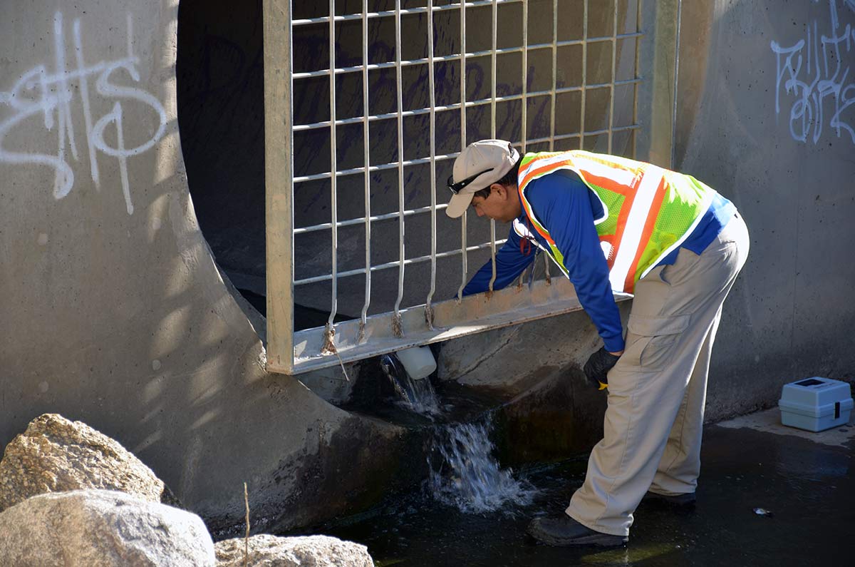 Water Services employee pulling a sample of stormwater runoff 