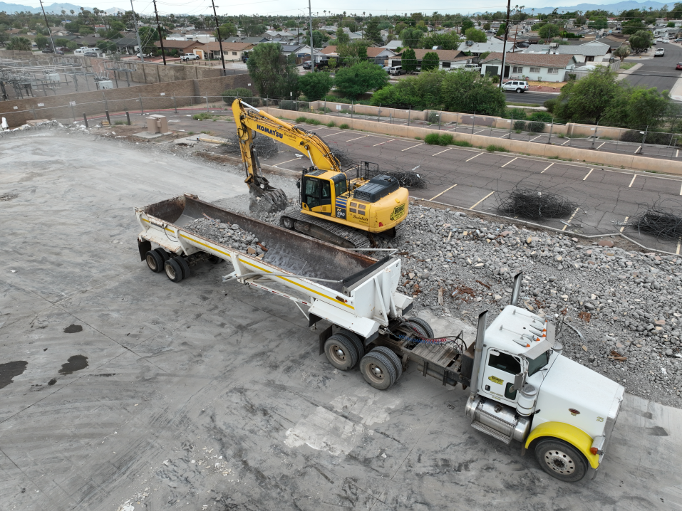 Semi truck being filled with debris by a track hoe after demolition of the former Fry's Electronics