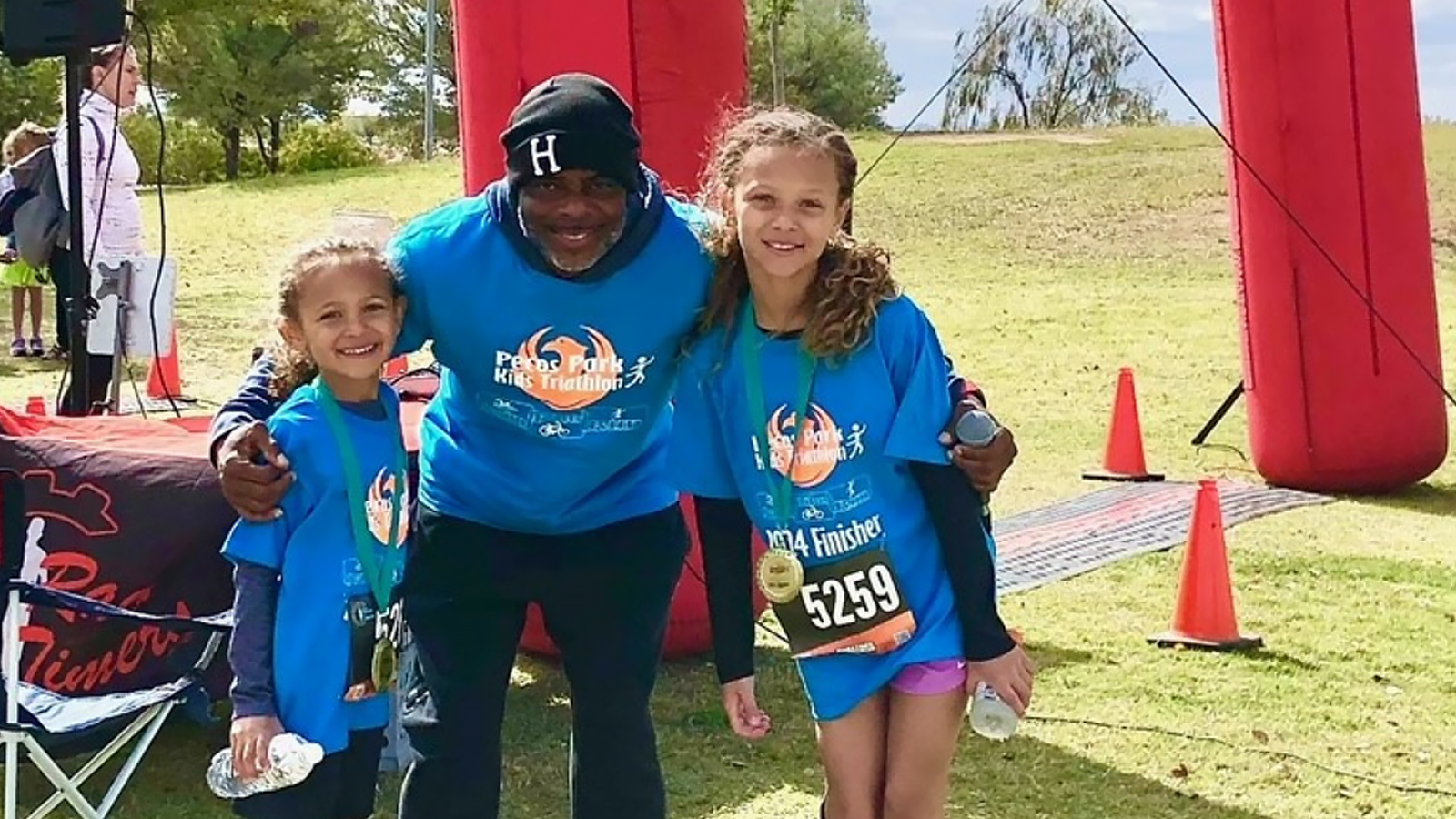 two children at the end of triathlon pose with an adult