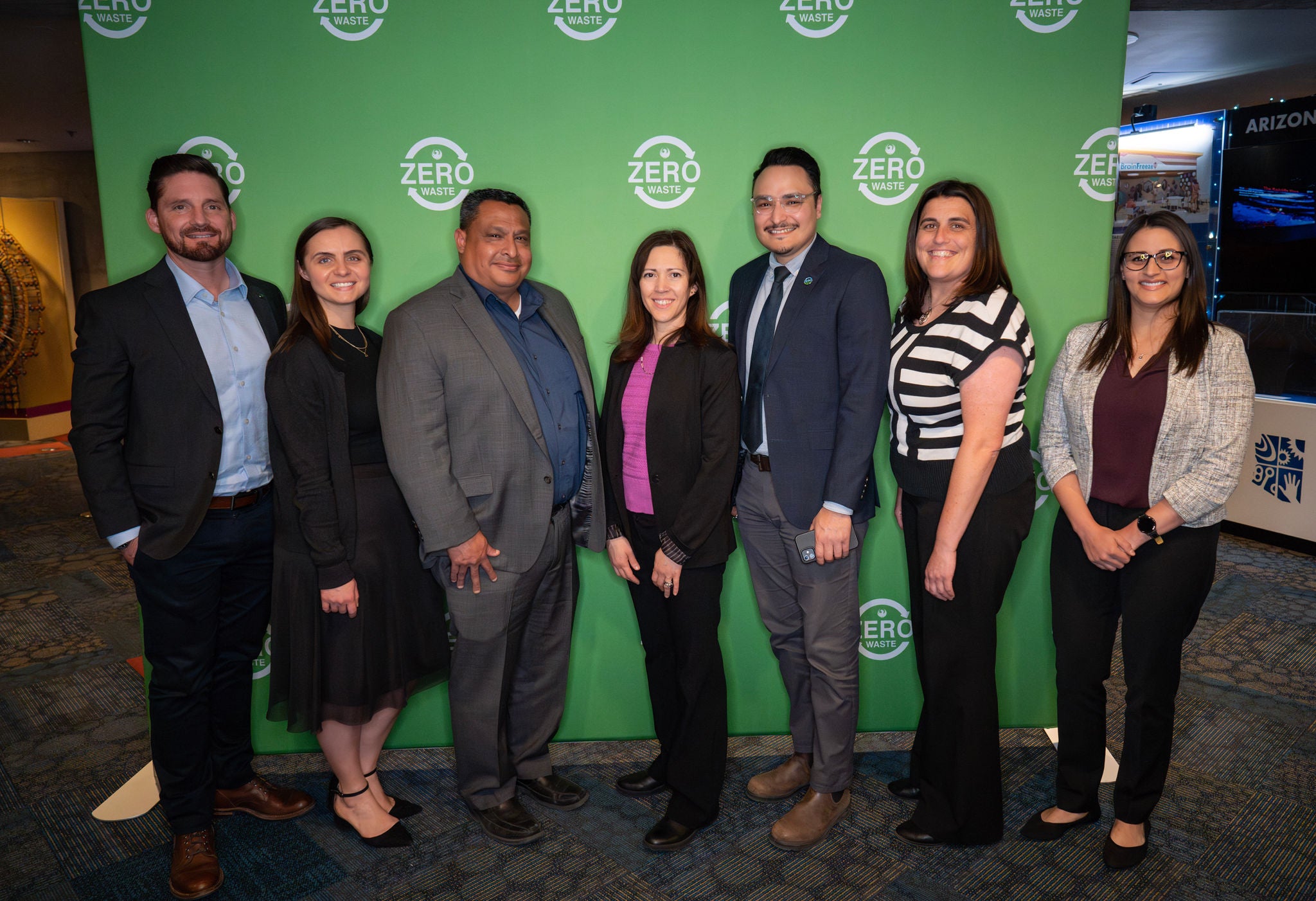 Phoenix Public Works Department employees pose together in front of the green, Zero Waste backdrop.
