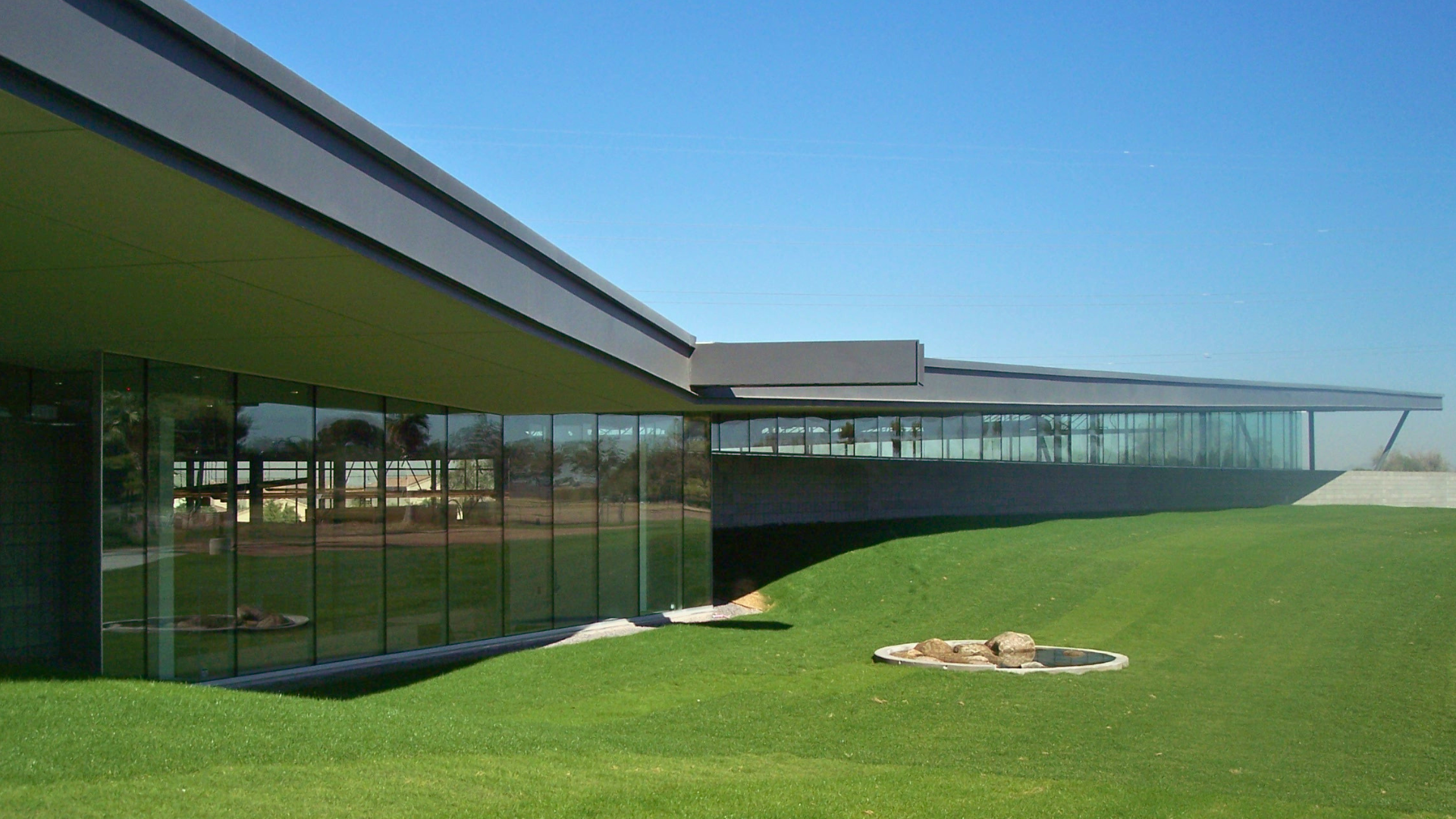Photo of the external building and lanscaping at the Phoenix Public Library in Laveen, taken during the day featuring blue sky and green grass.