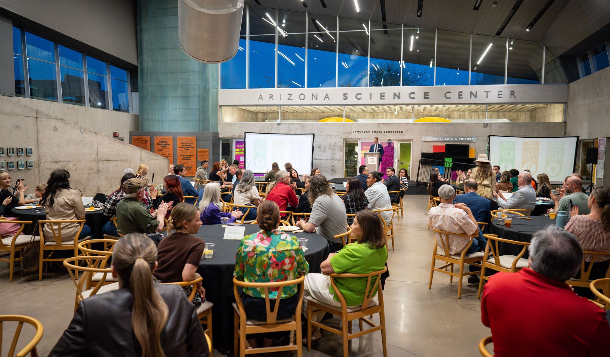 A wide shot of the crowd seated around tables and enjoying dinner at the Arizona Science Center.