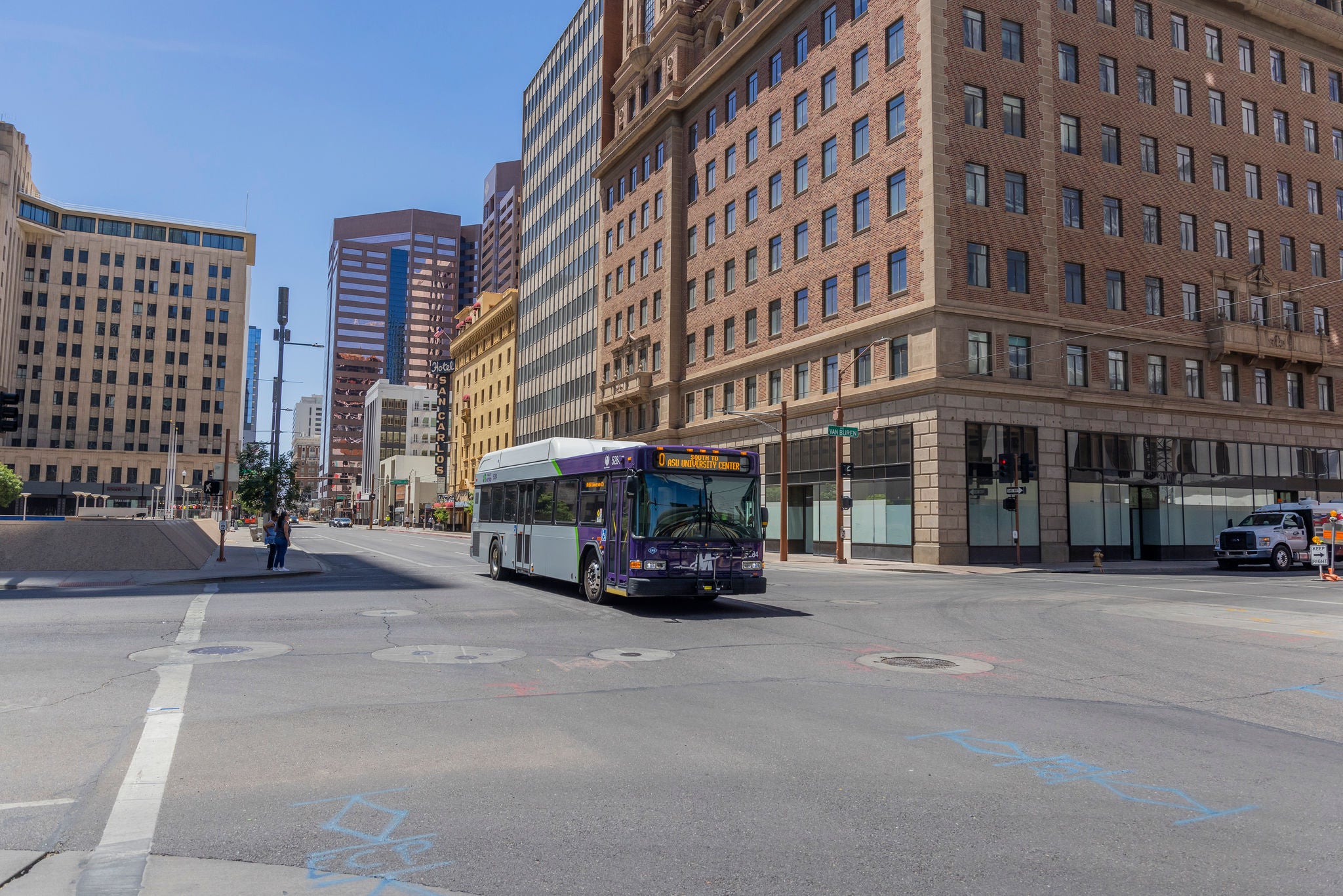 A Valley Metro bus driving north on Central avenue in Downtown Phoenix. The cityscape is in the background. 