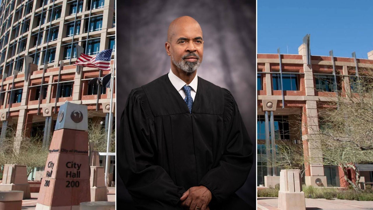 Judge standing for a photo in a black robe flanked by Phoenix City Hall on both sides