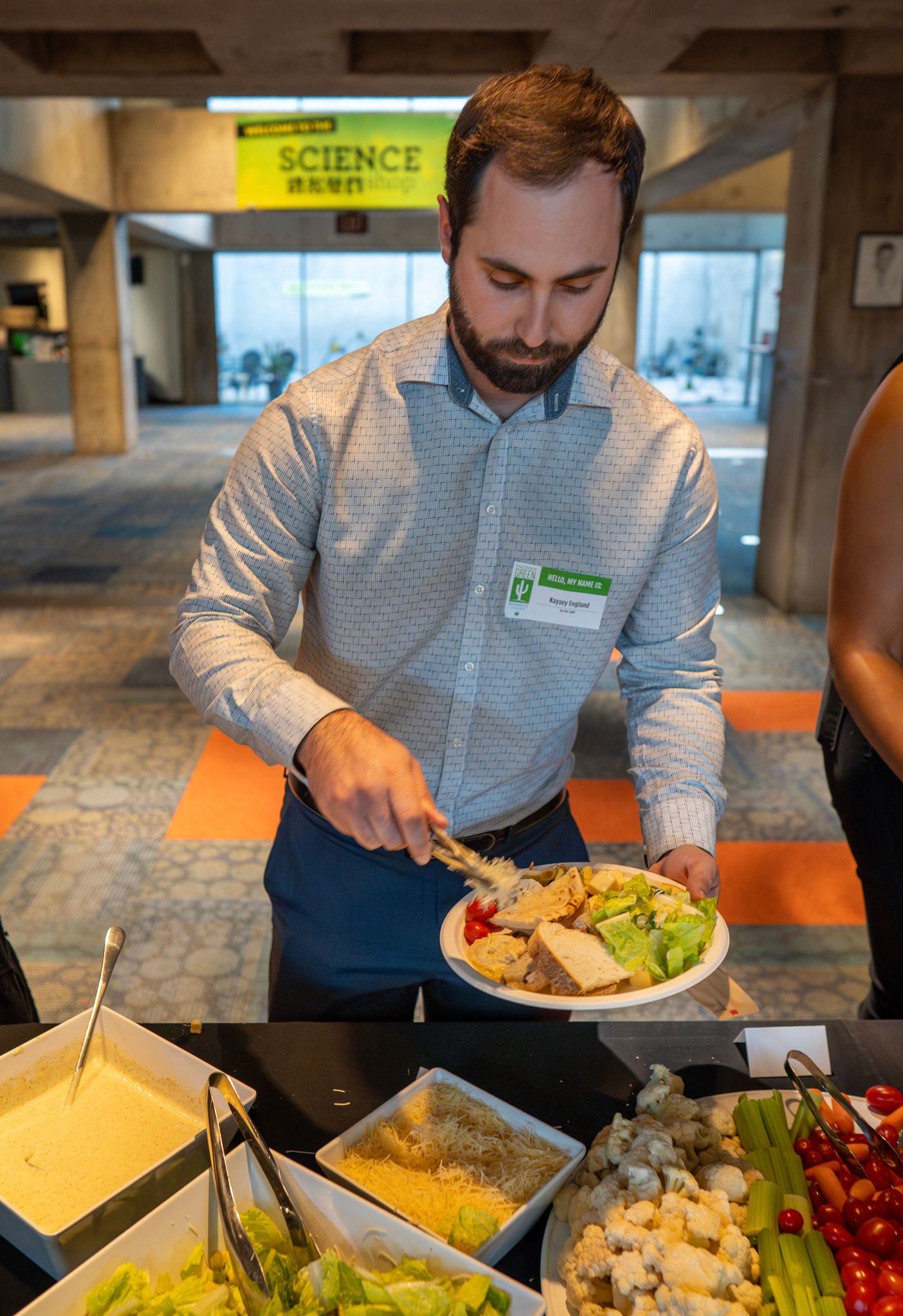 A Green Business Leader serves himself food from the dinner line