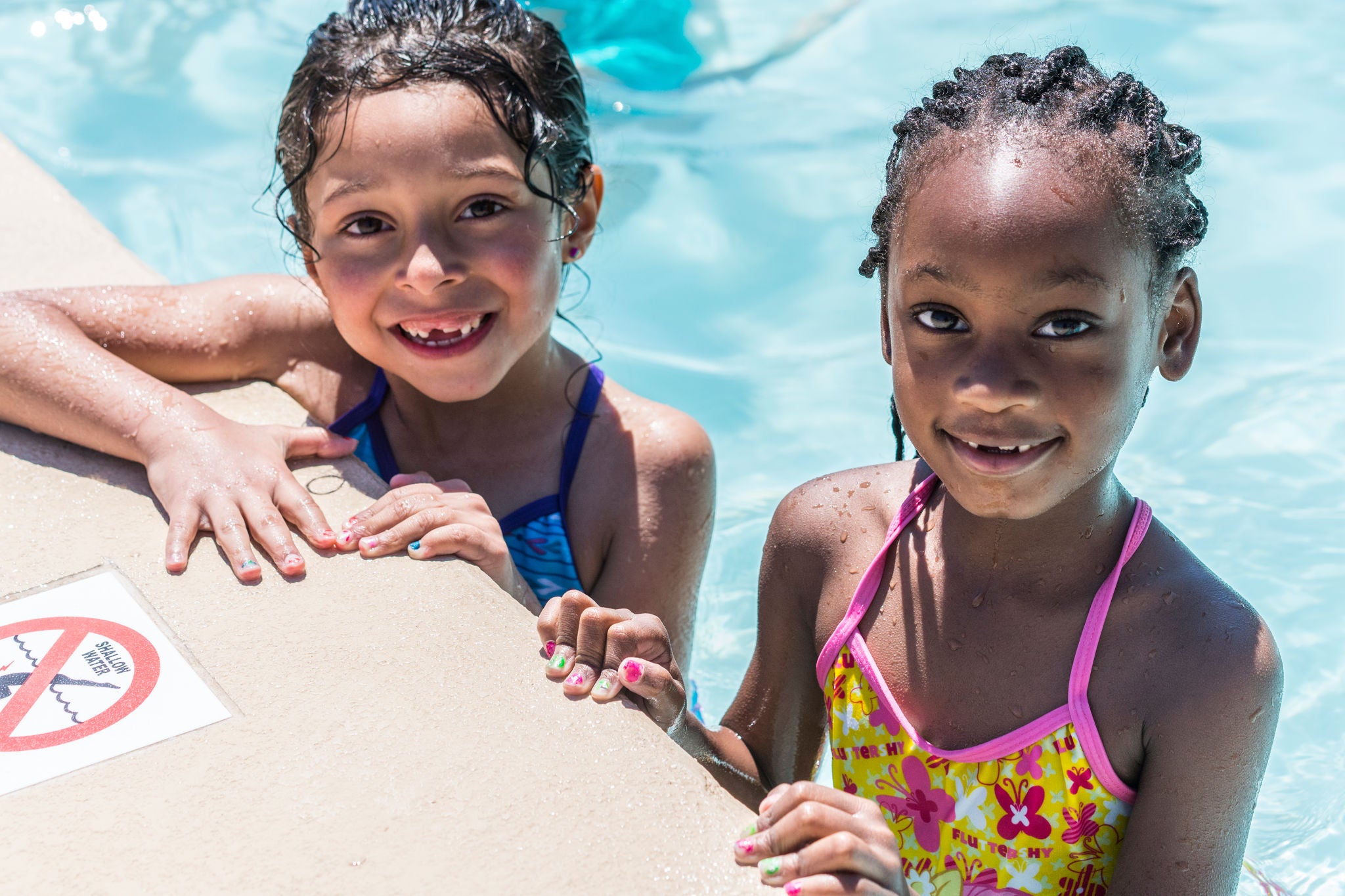 Two children smiling in a swimming pool.