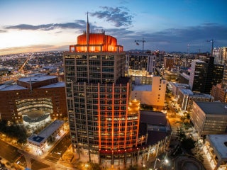 Arial photograph of Phoenix City Hall at dusk. The building is illuminated orange and is surrounded by city lights.