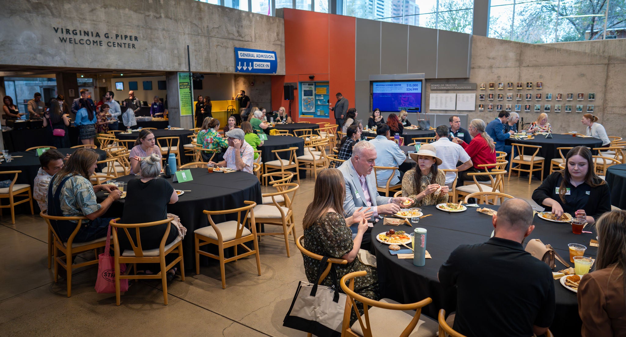 A wide shot of the crowd seated around tables and enjoying dinner at the Arizona Science Center.