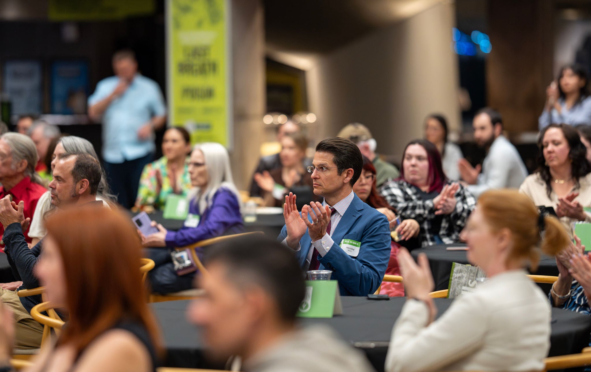A photo of the crowd seated around tables and clapping at the Arizona Science Center.