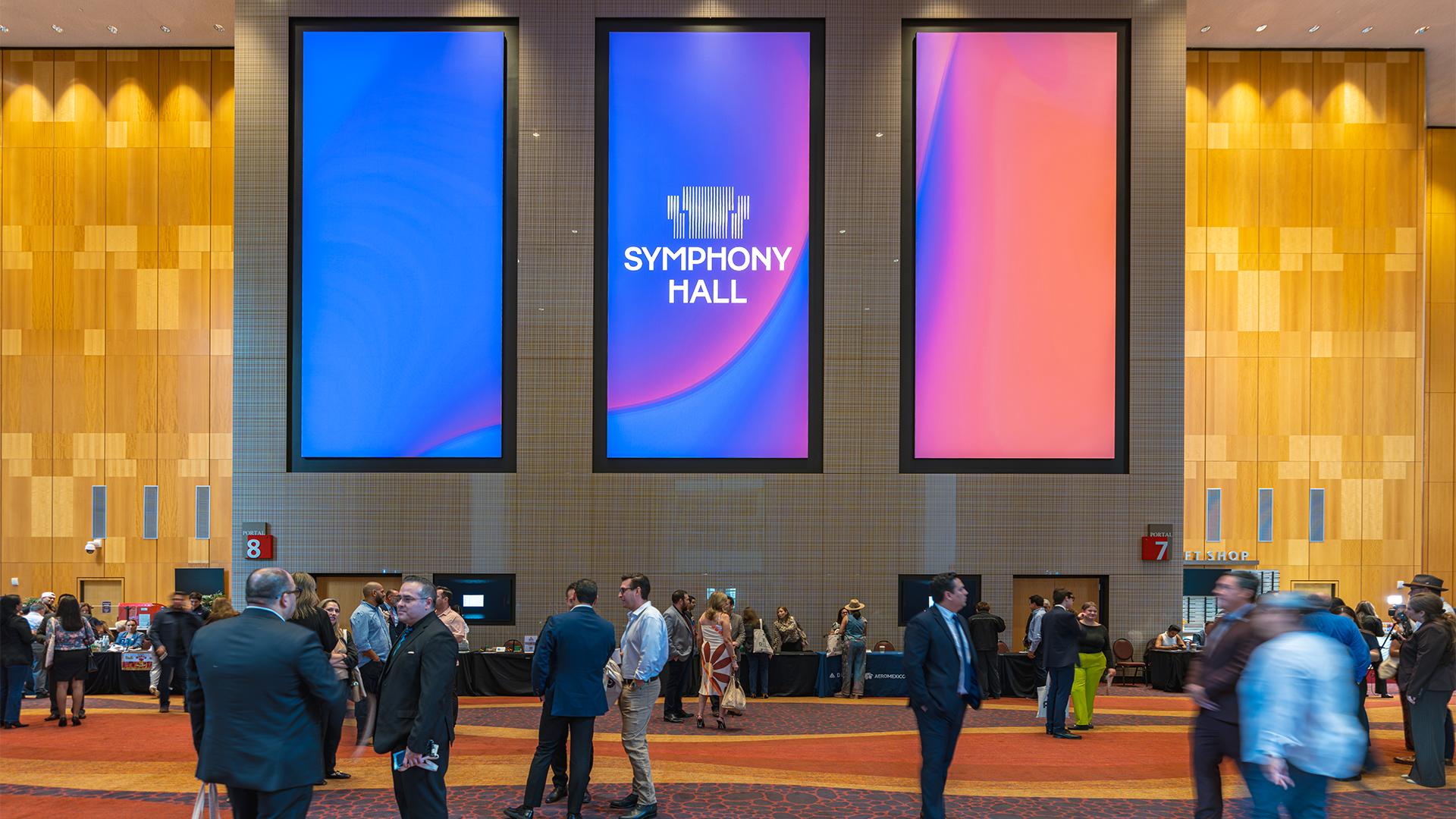 People in front of three new monitors inside Symphony Hall. 
