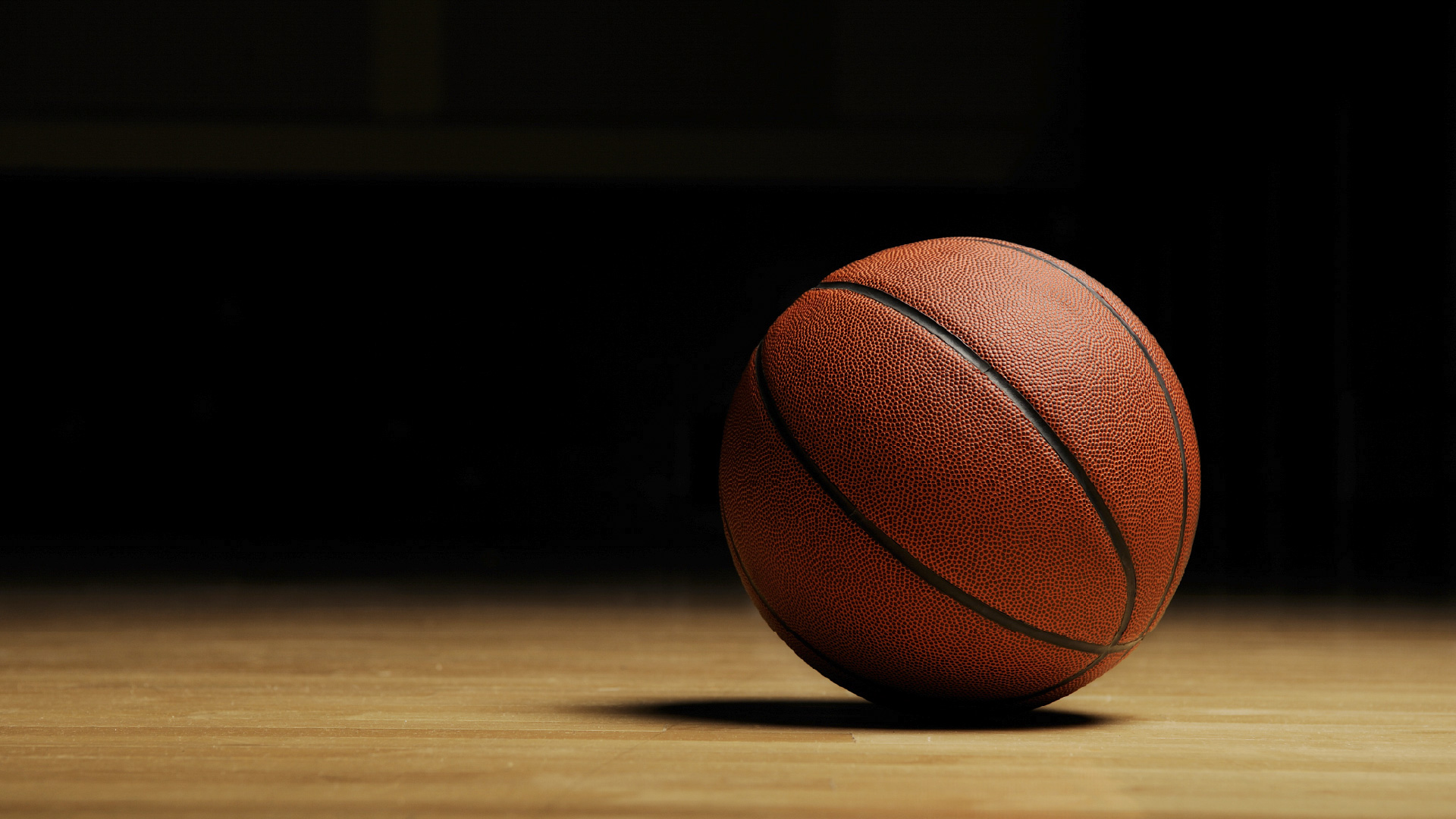Single Basketball on a wood court with a dark background