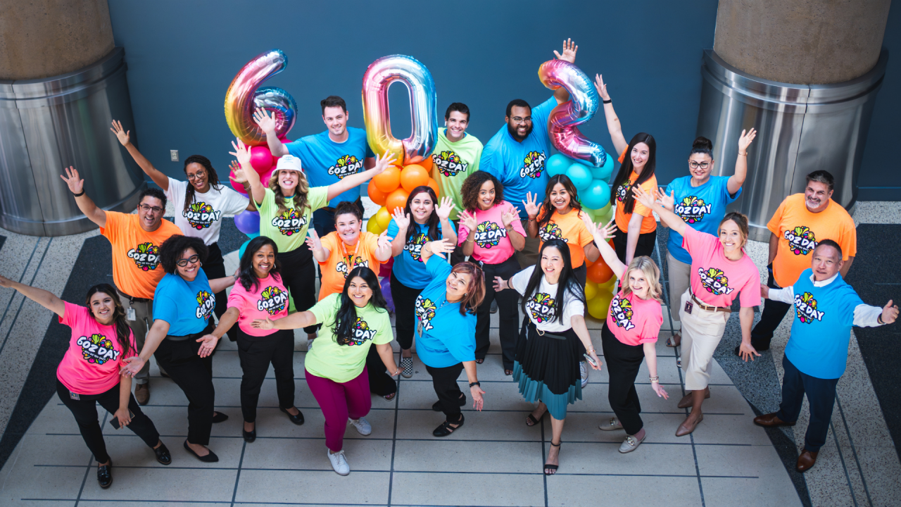 Group of people wearing colorful shirts that say "602 Day" and large colorful "602" balloons
