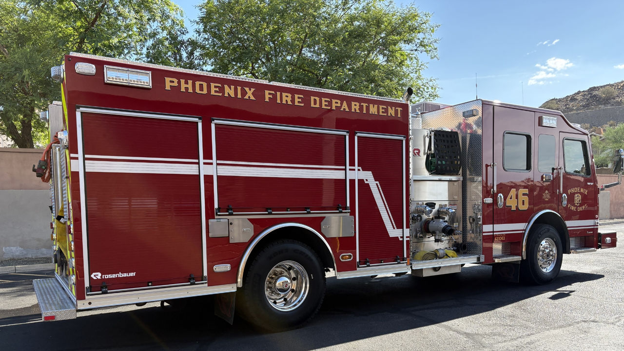 Fire Engine 46 parked outside its fire house on a sunny day