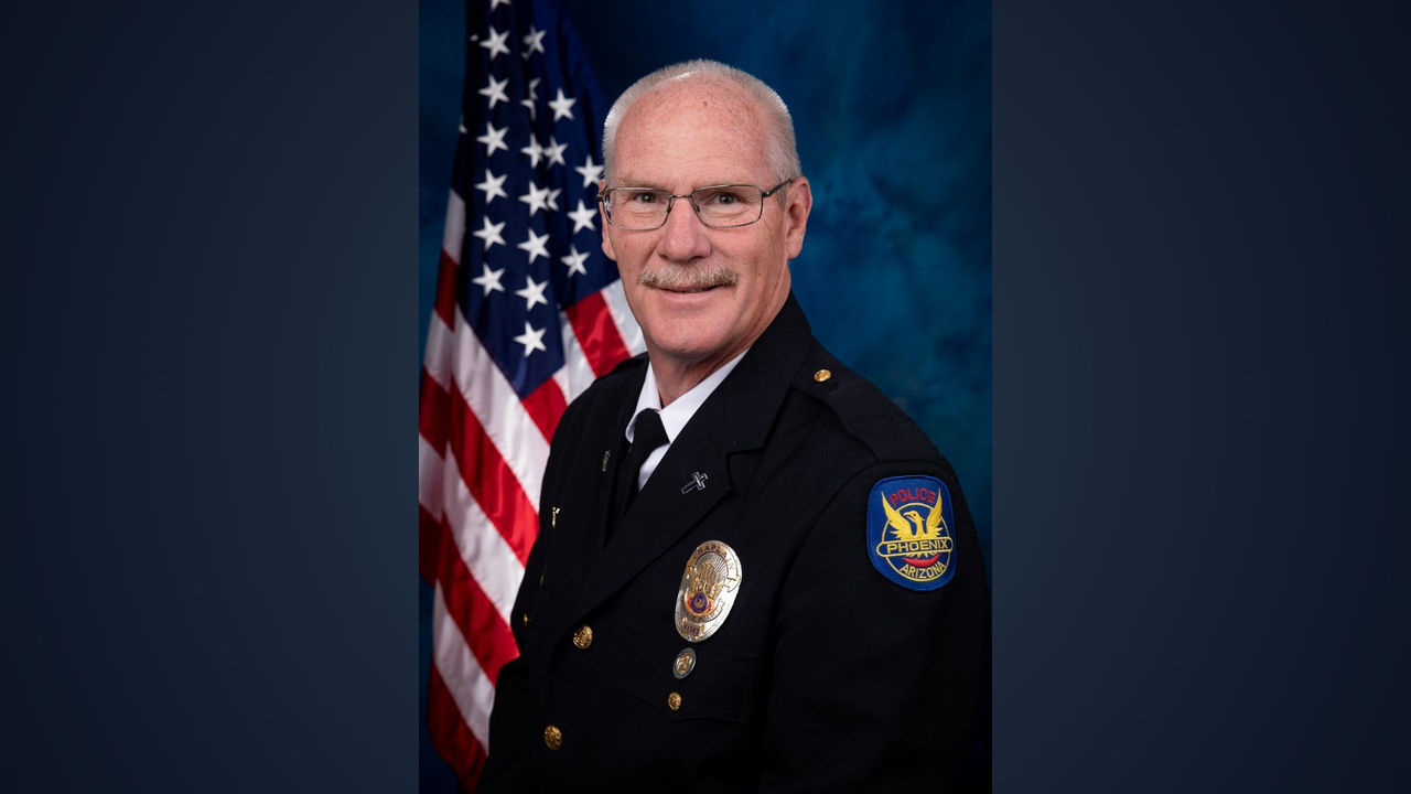 Chaplain Bob Fesmire sitting in front of a blue background with an American flag
