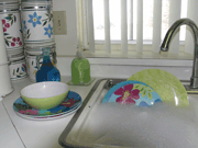 Kitchen sink containing soapy water and colorful plastic dishes.