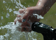 Hand gets sprayed with water from a nozzle.