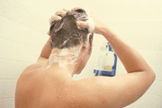 Man washing hair in shower stall.