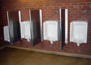A row of four men's urinals attached to a brick wall.