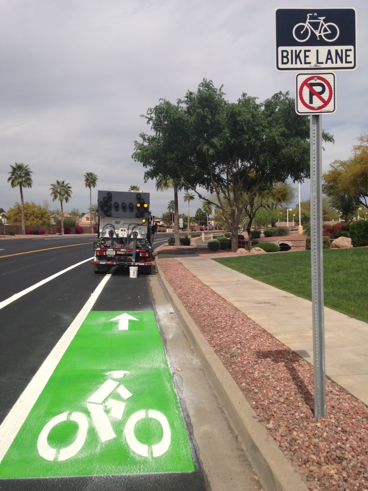 Green bike lane with white symbols being painted
