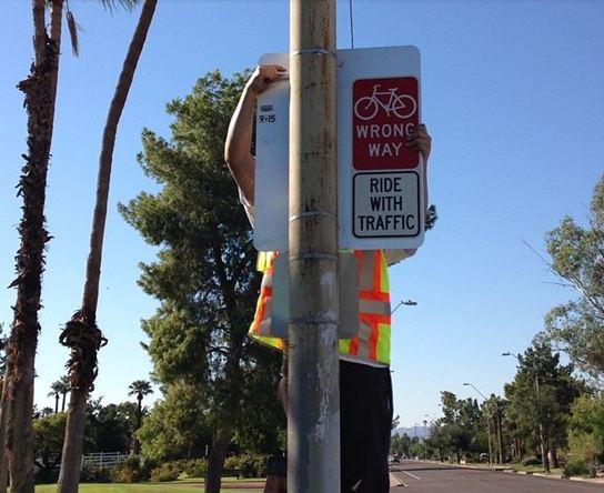 Wrong way sign being hung on pole